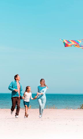 Familia en la playa volando una cometa