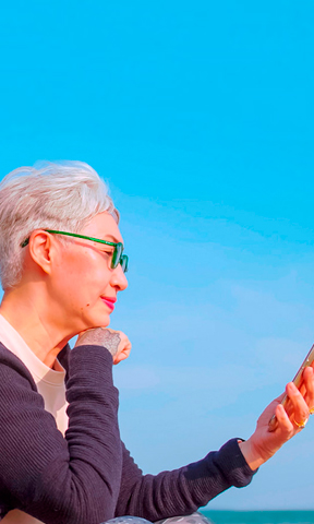 Mujer viendo su móvil en la playa.