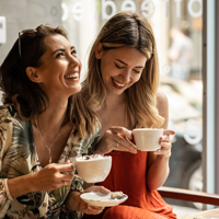 Amigas riéndose mientras se toman un café