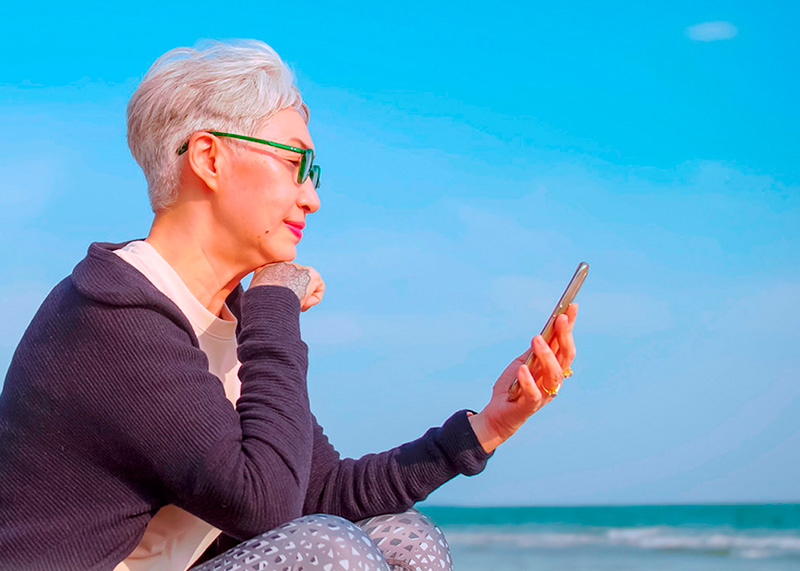 Mujer observando su móvil en la playa.