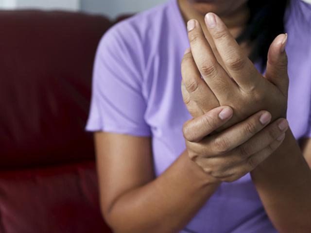 Mujer sujetándose la mano con gesto de dolor o molestia, síntoma asociado al hormigueo en las manos